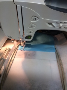 Fold the fabric back all the way behind the hoop, folding over the last row of stitching